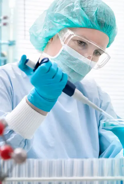 Laboratorytechniker in Schutzkleidung verwendet eine Pipette zur präzisen Messung von Flüssigkeiten in einem medizinischen Umfeld.